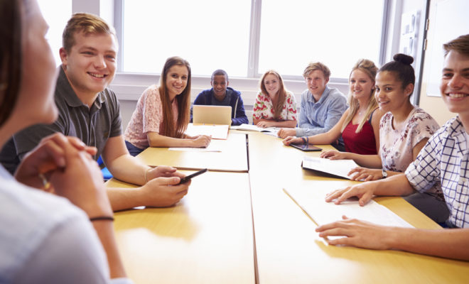 Group Of College Students Sitting At Table Having Discussion